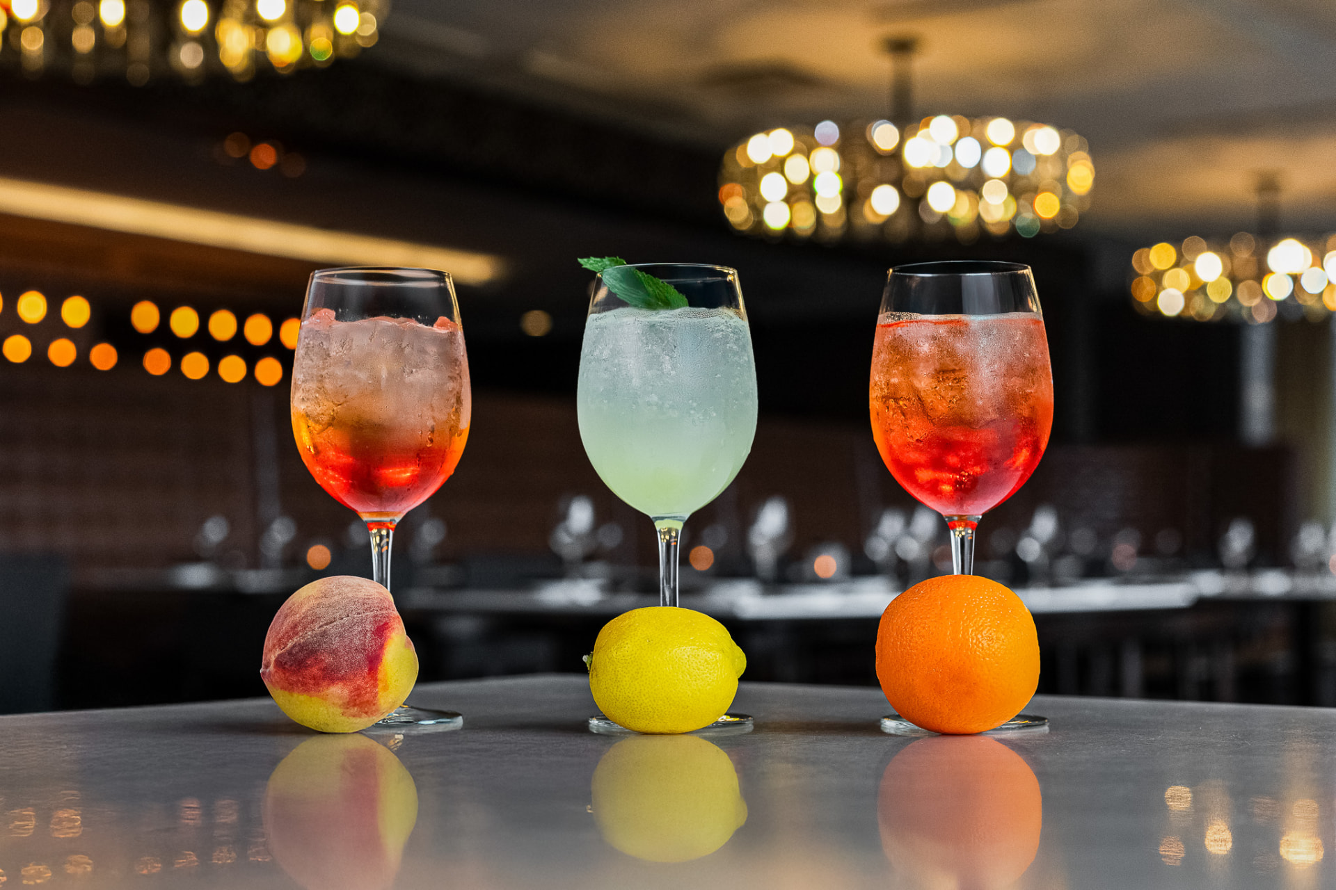 Three spritz cocktails on the bar with citrus garnishes