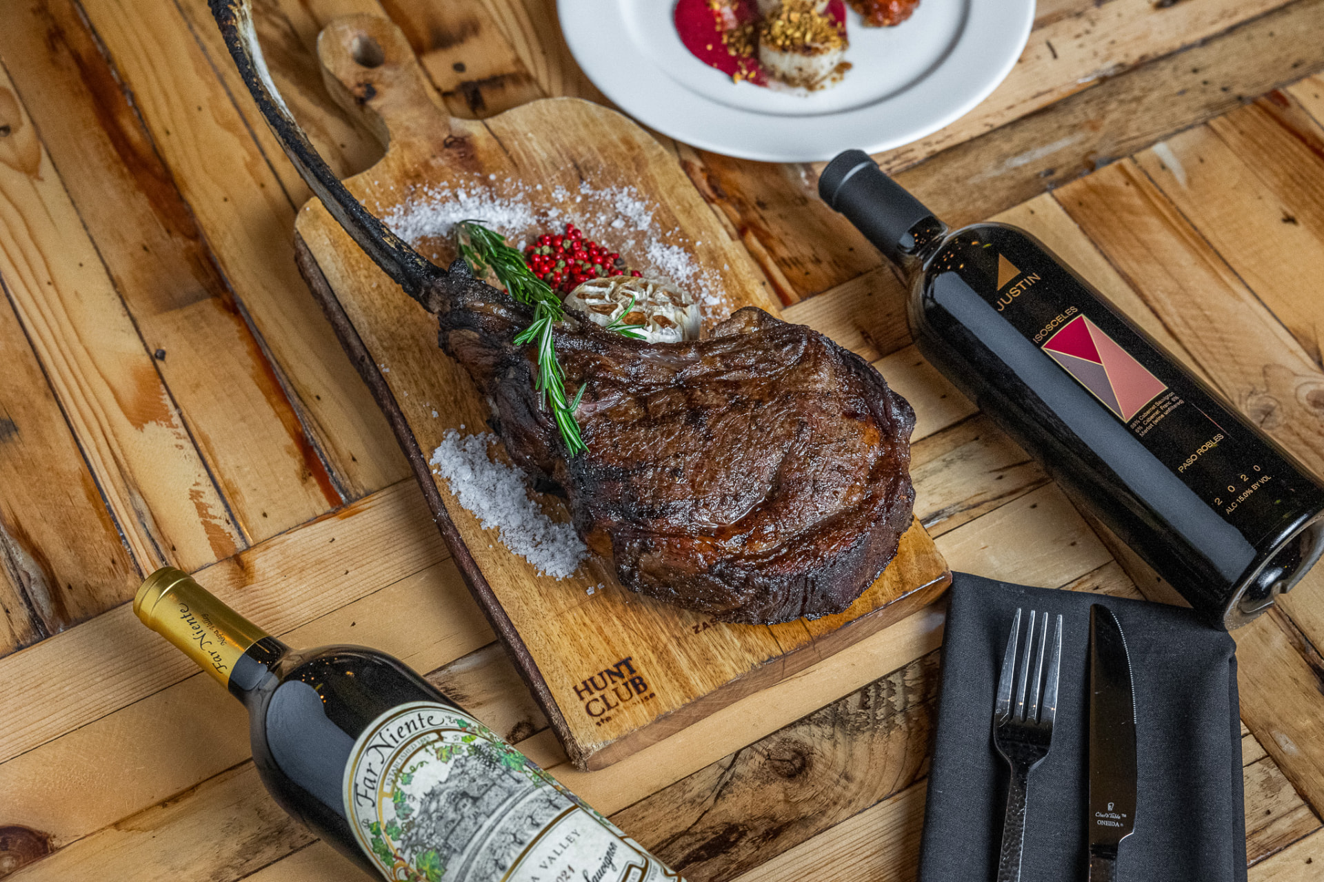 Tomahawk ribeye on a board with wine bottles